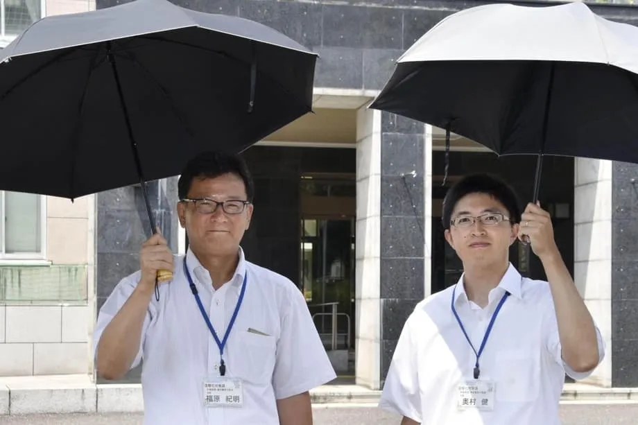Im glühend heißen Japan greifen Männer zum Sonnenschirm, um sich abzukühlen